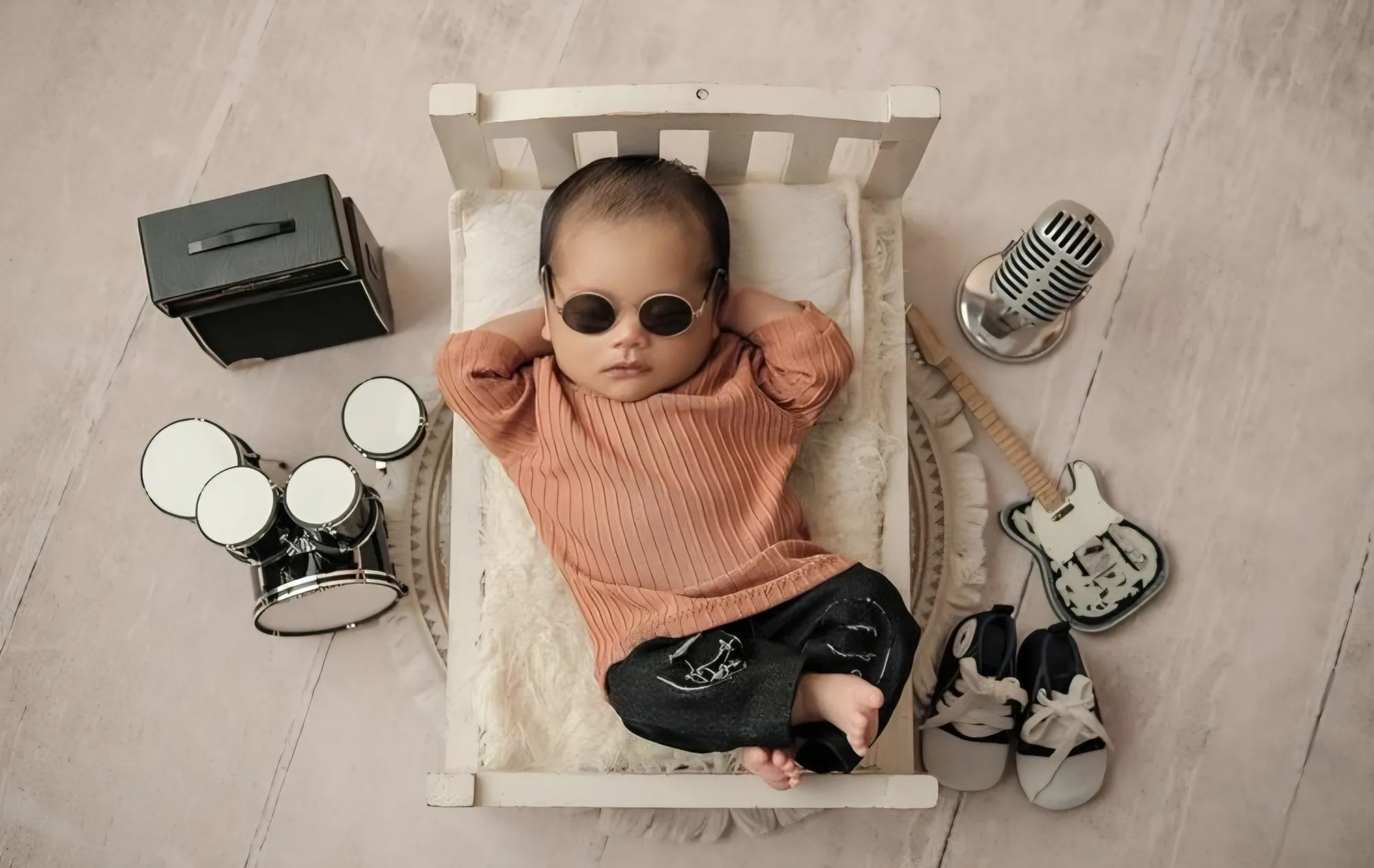Baby wearing sunglasses beside miniature musical instruments
